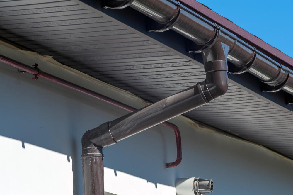 "Close-up of angled metal rain gutter and downspout system on modern residential roof"