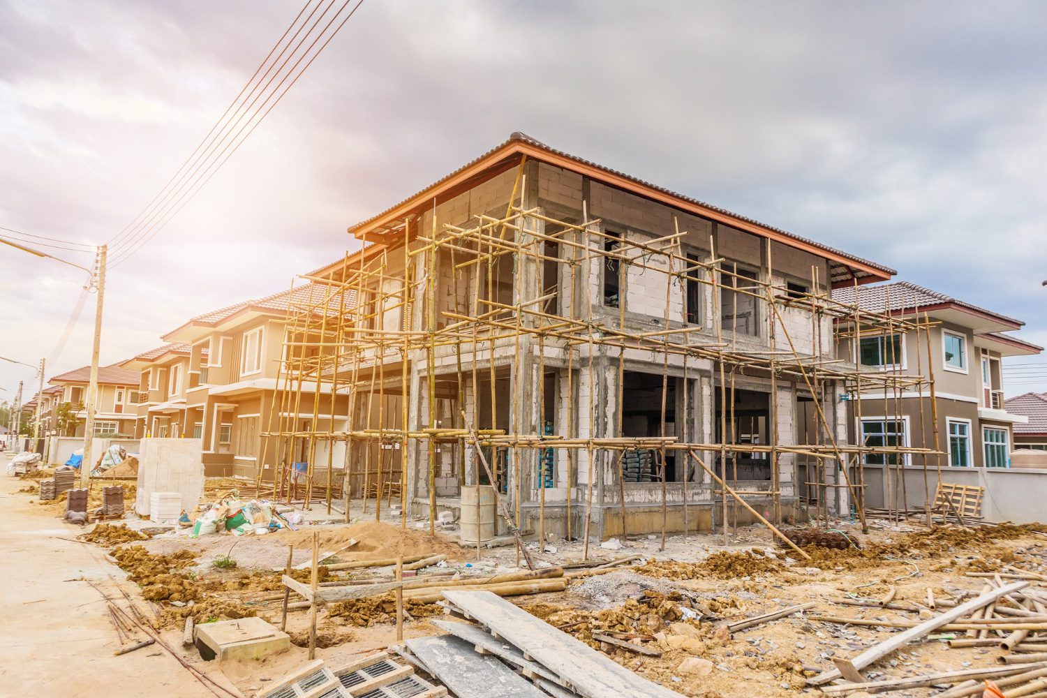 "Two-story concrete house under construction with scaffolding and exposed structure"