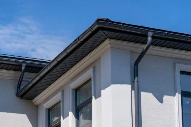 "Modern white house with black metal gutters and downspouts installed along the roofline"