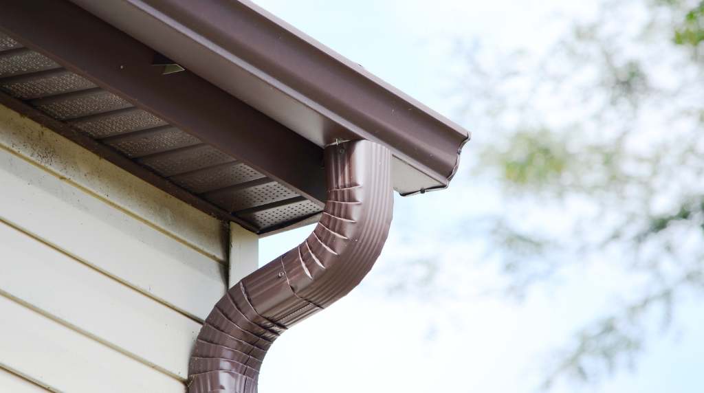 Curved downspout attached to gutter system for efficient rainwater flow
