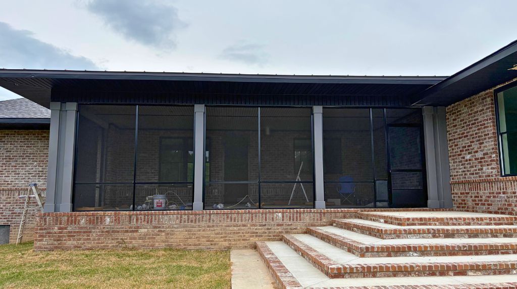 Exterior view of a custom aluminum screen room installation with screened walls and patio access in Tennessee