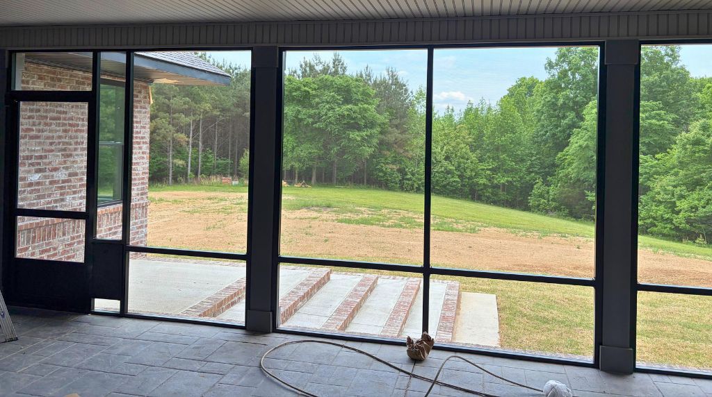 Interior aluminum screen room with large screened openings overlooking a backyard landscape in South Tennessee
