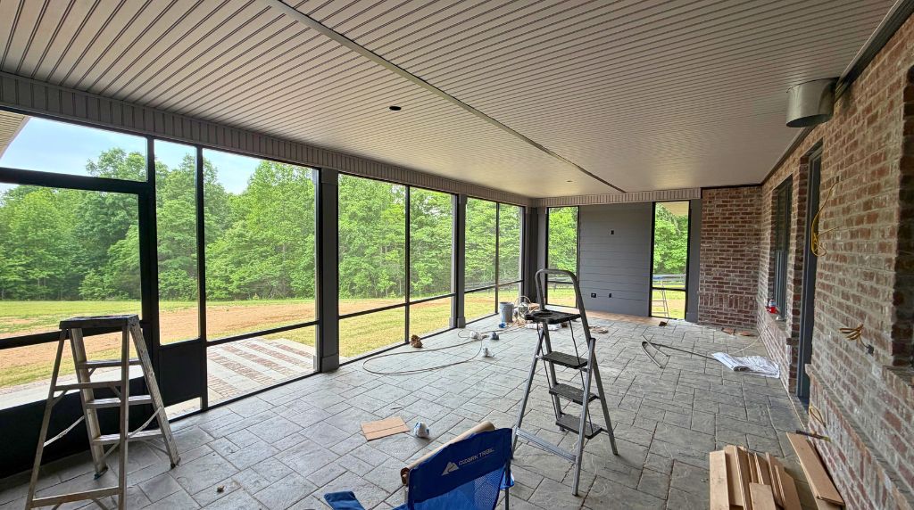 Spacious covered aluminum screen porch under construction with screened walls and outdoor living area