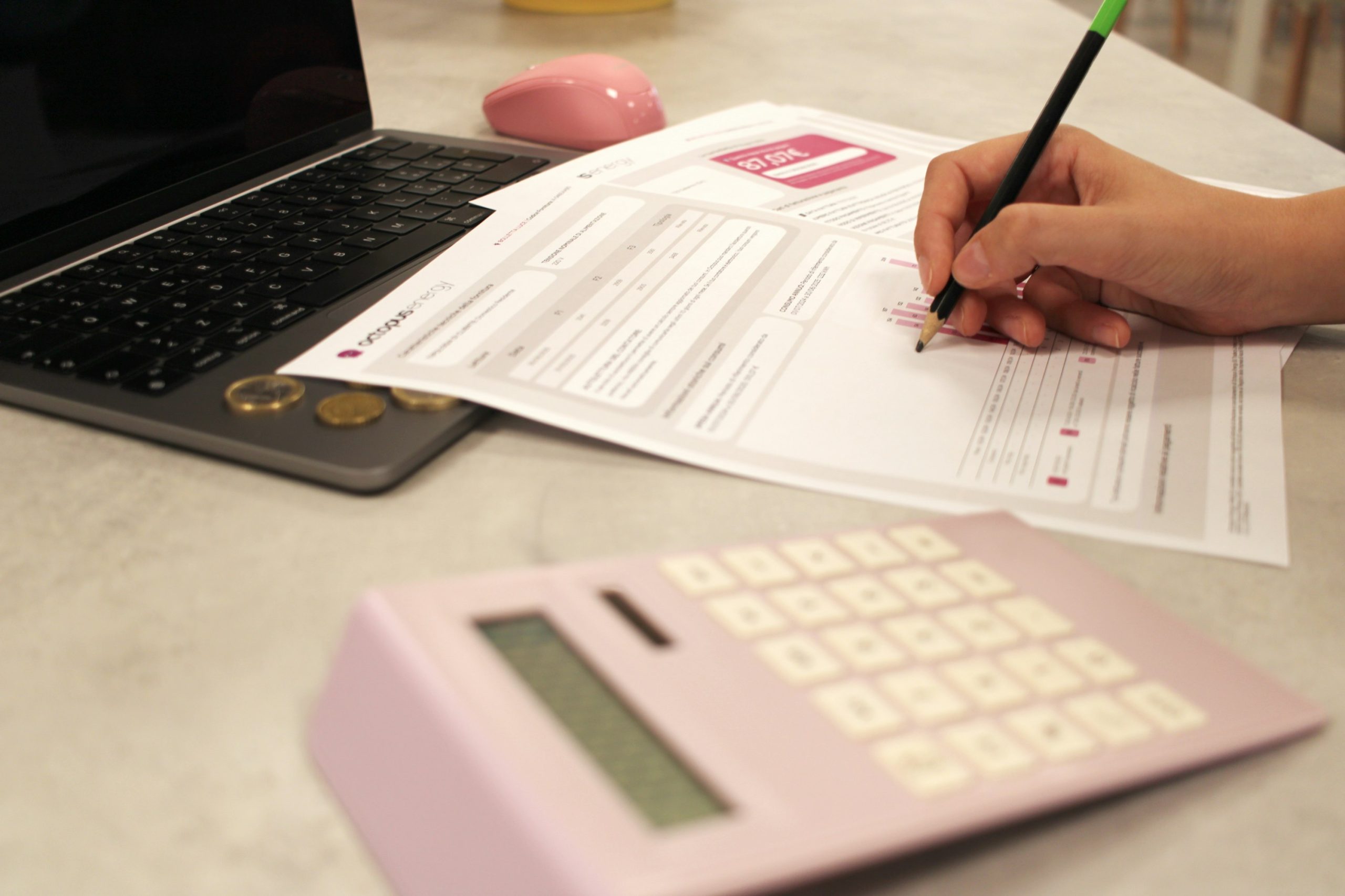 Home warranty cost image with a calculator and budget paperwork on a desk.