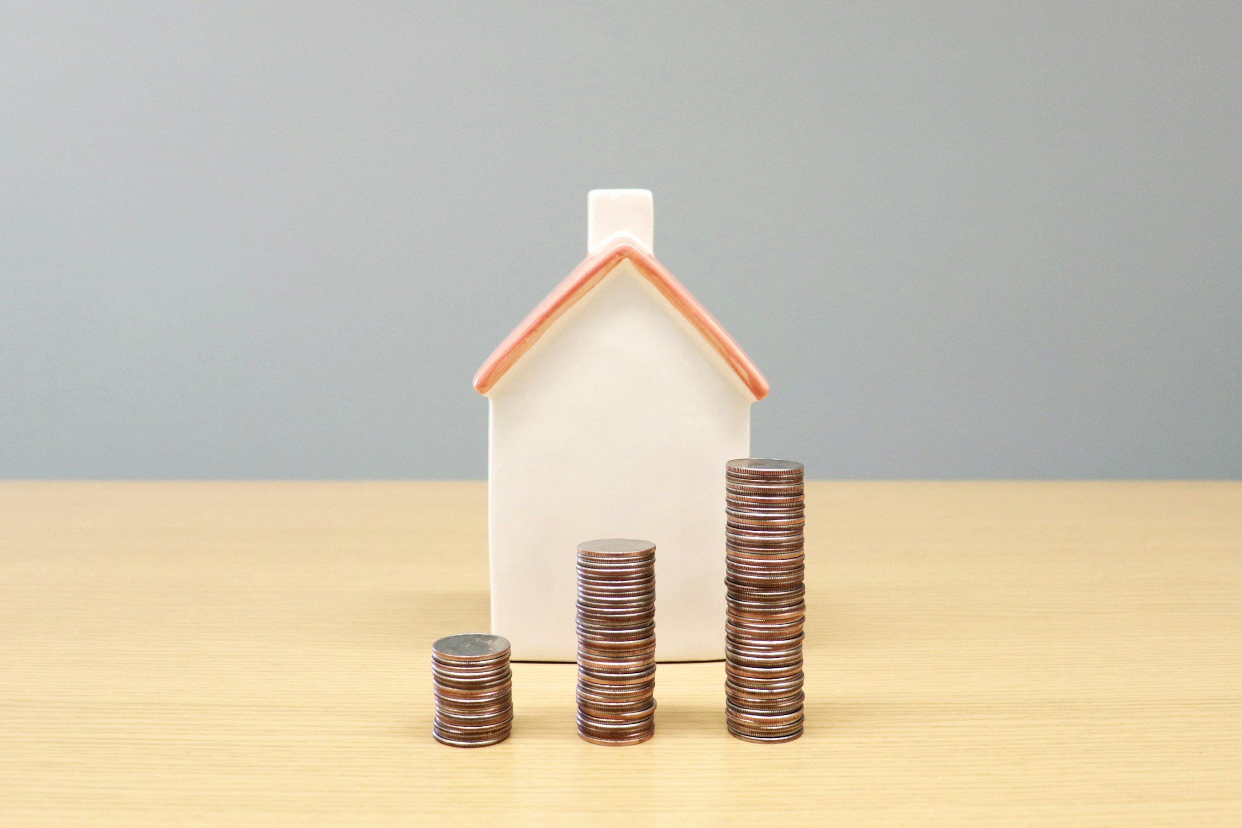 Home warranty cost image showing a small house model beside stacked coins.