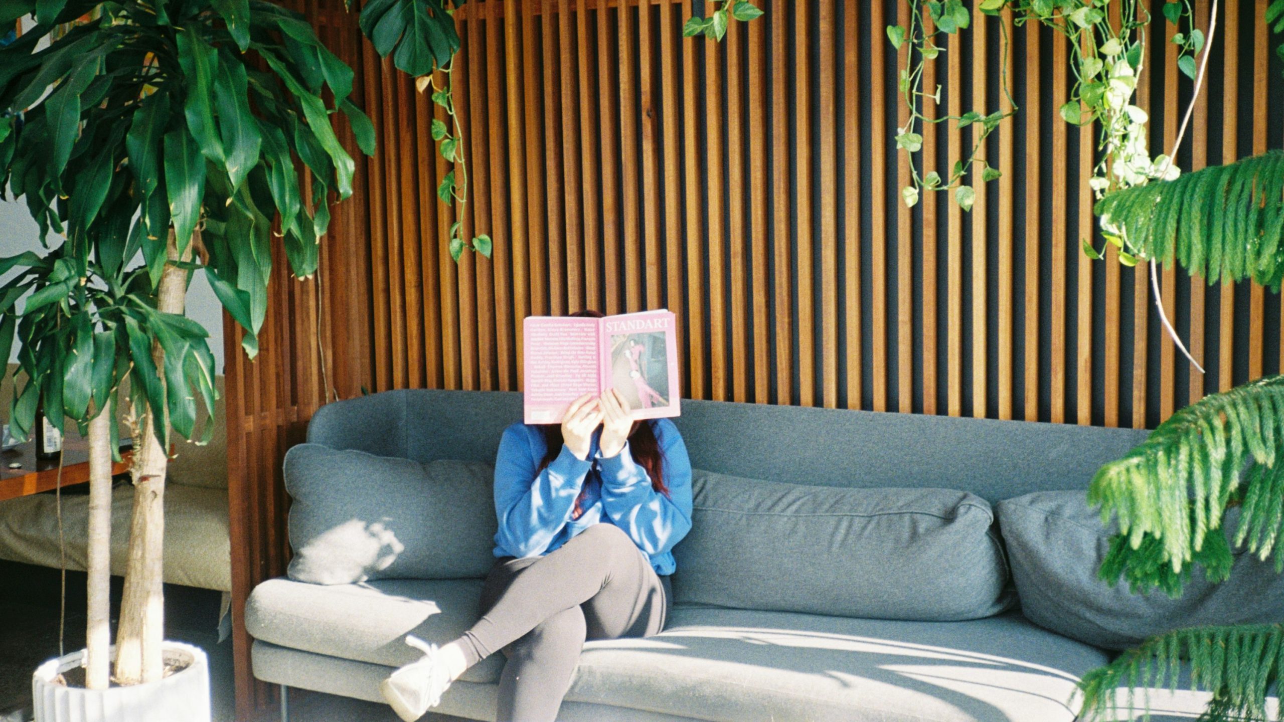 Person reading a home warranty guide on a couch in a comfortable home setting.
