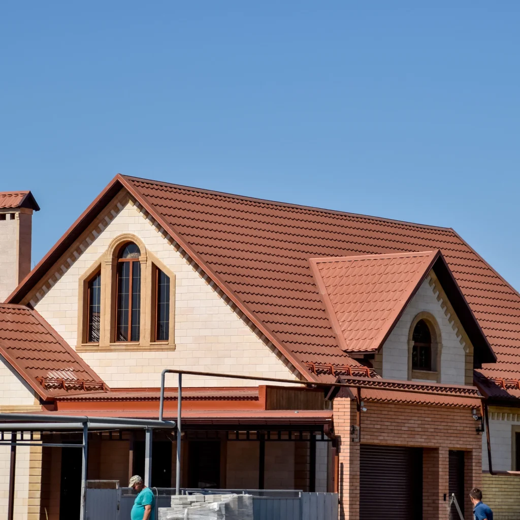 "Newly constructed house with red tiled roof and arched windows under clear blue sky"